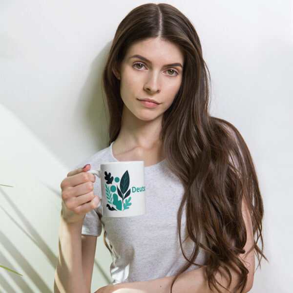 Weiße Keramiktasse mit dem Aufdruck „Deutschland bleibt grün“ und abstraktem Blattmotiv. Statement-Becher für Umweltschutz, Klimaschutz und nachhaltigen Konsum. 11 oz Fassungsvermögen, spülmaschinen- und mikrowellengeeignet, ideal für Kaffee, Tee und heiße Getränke im Alltag.